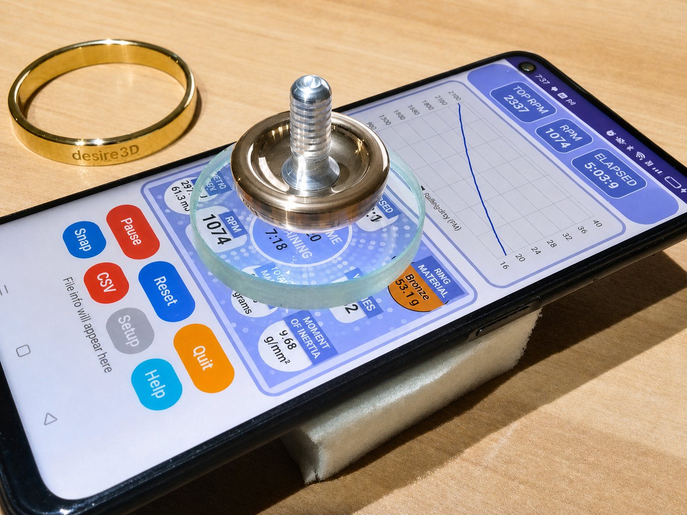 TopSpin test setup with a phone on foam, glass disc, brass ring, and spinning top